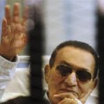Former Egyptian President Mubarak waves inside a cage in a courtroom at the police academy in Cairo