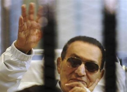 Former Egyptian President Mubarak waves inside a cage in a courtroom at the police academy in Cairo