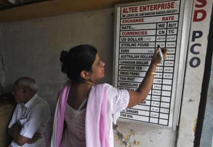 A shopkeeper writes currency exchange rates on a board inside a currency exchange shop in Kolkata