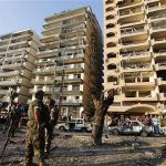 Lebanese army soldiers stand near damaged buildings caused by the two explosions outside two mosques in Lebanon's northern city of Tripoli