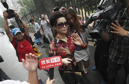 Singer Meng gestures as she is surrounded by the media outside a court in Beijing