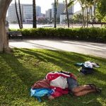 a man sleeps on the ground near Waikiki Beach