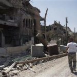 Free Syrian Army fighters walk past damaged buildings and debris in Deir al-Zor