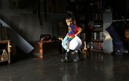 Rowen Roberson carries clothes from his flooded garage in Longmont