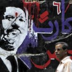 A man walks past graffiti depicting ousted Egyptian President Mursi in downtown Cairo