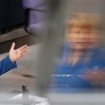 German Chancellor Merkel is reflected in a window as she gives a speech during a debate of the lower house of parliament Bundestag in Berlin