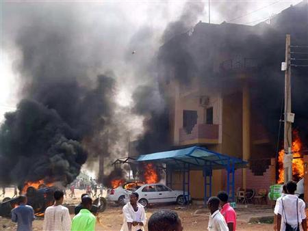 Cars burn in front of a building during protests over fuel subsidy cuts in Khartoum