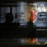 A visitor walks past logos at the TSE in Tokyo