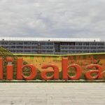 A worker walks past a logo of Alibaba Group at its headquarters on the outskirts of Hangzhou