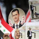 A student holds a sign with a picture of Syria's President Bashar al-Assad during a protest by a students' national union against possible U.S. military action in Syria, in Brasilia