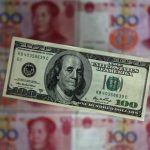 A photo illustration shows a $100 banknote placed above Chinese 100 yuan banknotes in Beijing