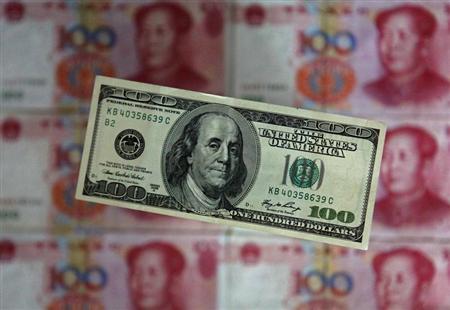 A photo illustration shows a $100 banknote placed above Chinese 100 yuan banknotes in Beijing