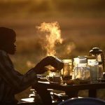 A woman prepares tea at an outdoor coffee shop near a polling station located in a school during a referendum in the town of Abyei