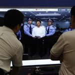 Men look at a picture of disgraced Chinese politician Bo standing trial on the website of a court's microblog, in Jinan