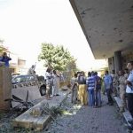 Security personnel and residents gather at the scene of a car bomb explosion at the Swedish consulate in Benghazi