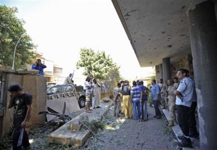 Security personnel and residents gather at the scene of a car bomb explosion at the Swedish consulate in Benghazi