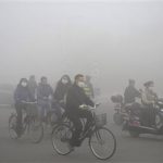 People ride along a street on a smoggy day in Daqing