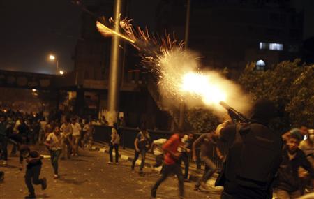 A riot police officer fires tear gas during clashes between anti-Mursi protesters, and members of the Muslim Brotherhood and ousted Egyptian President Mohamed Mursi supporters, in Cairo