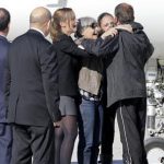 Former French hostage Larribe is welcomed by relatives as French President Hollande and French Defence Minister Le Drian look on on the tarmac upon their arrival at Villacoublay military airport, near Paris