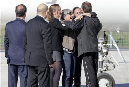 Former French hostage Larribe is welcomed by relatives as French President Hollande and French Defence Minister Le Drian look on on the tarmac upon their arrival at Villacoublay military airport, near Paris