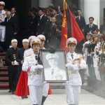 Soldiers hold up the portrait of the late General Vo Nguyen Giap as his coffin is carried during his funeral at the National Funeral House in Hanoi