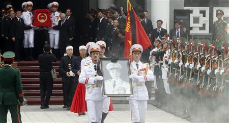 Soldiers hold up the portrait of the late General Vo Nguyen Giap as his coffin is carried during his funeral at the National Funeral House in Hanoi
