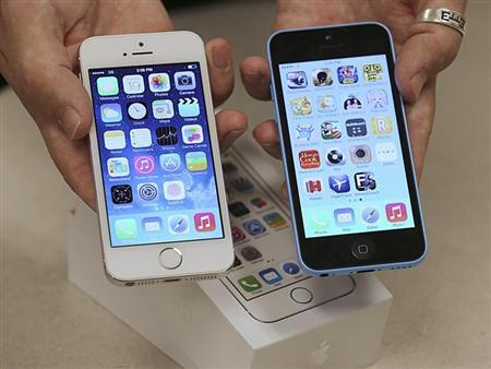 An employee shows the the front of a new Apple iPhone 5C and iPhone 5 S at a Verizon store in Orem, Utah