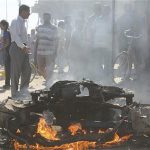 People look at the site of a car bomb attack in Diwaniya