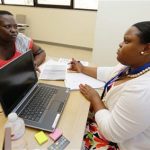 A Certified Application Counselor takes information from woman inquiring about Affordable Care Act insurance in Miami