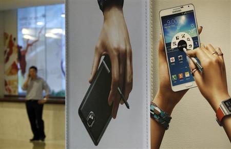 A man talks on his mobile phone near advertisements promoting the Samsung Electronics' Galaxy Note 3 at the company's headquarters in Seoul