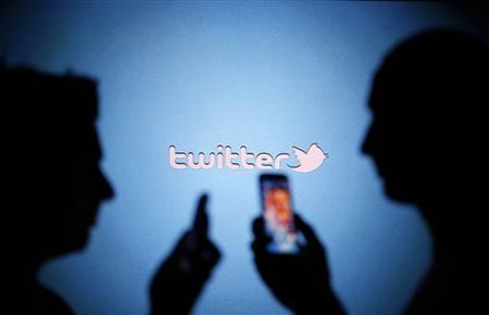 Men are silhouetted against a video screen with a Twitter logo as they pose with Samsung S3 and S4 smartphones in this photo illustration taken in the central Bosnian town of Zenica in this file photo