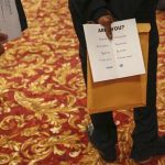 Man holds a pamphlet handed out by a recruiter while attending a job fair in New York