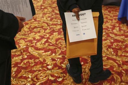 Man holds a pamphlet handed out by a recruiter while attending a job fair in New York
