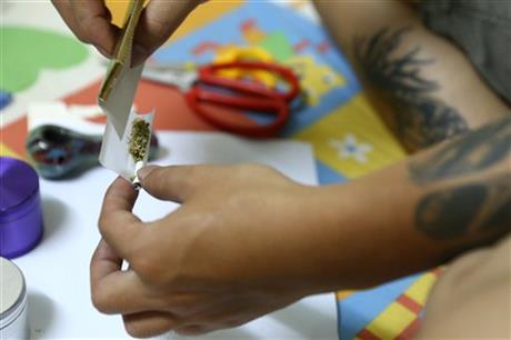 a man rolls a joint with Canadian-grown marijuana