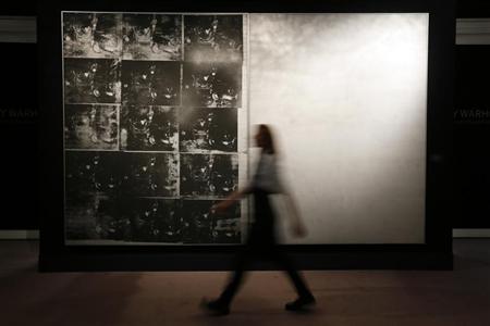 A Sotheby's employee poses with Warhol's artwork "Silver Car Crash" at Sotheby's auction house in London