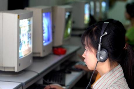 School girl uses headphone while surfing web at public cafe internet in Hanoi