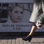 A woman walks past a portrait of jailed former Ukrainian PM and opposition leader Tymoshenko at a protest tent camp set up by her supporters in central Kiev