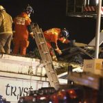 Firefighters and rescuers inspect the damage on the building at the site of a helicopter crash