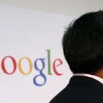 A man stands in front of a Google logo in Hong Kong