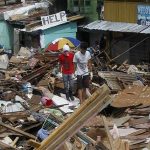 Residents walk past houses devastated by Typhoon Haiyan in Tacloban city, central Philippines