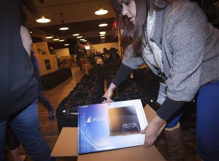 A Sony employee takes a Playstation 4 out of the box in advance of a special sale event put on by Sony at the Standard Hotel in New York