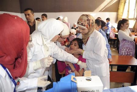 Syrian health workers administer polio vaccination to a girl at a school in Damascus