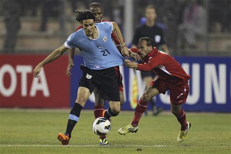 Edinson Cavani of Uruguay fights for the ball with Adnan Adous of Jordan during their World Cup qualifying playoff first leg soccer match at Amman International stadium