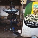 Men sit next to a painting of the ex-junta leader Amadou Haya Sanogo in Bamako