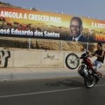 A motorcyclist rides past an election poster of the ruling MPLA party with the picture of President Jose Eduardo dos Santos in the capital Luanda