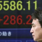 A man walks by an electronic stock board