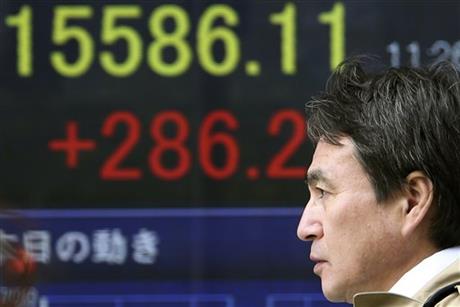 A man walks by an electronic stock board