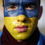 Man with his painted in the colours of the Ukranian flag poses for a portrait at Independence Square in Kiev