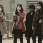 Women wear masks while walking on a bridge during a hazy day in Shanghai's financial district of Pudong