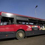 Riot police and investigators surround a damaged bus after a bomb blast in Cairo